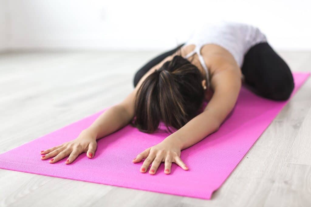 woman stretching on a yoga mat in workout clothes